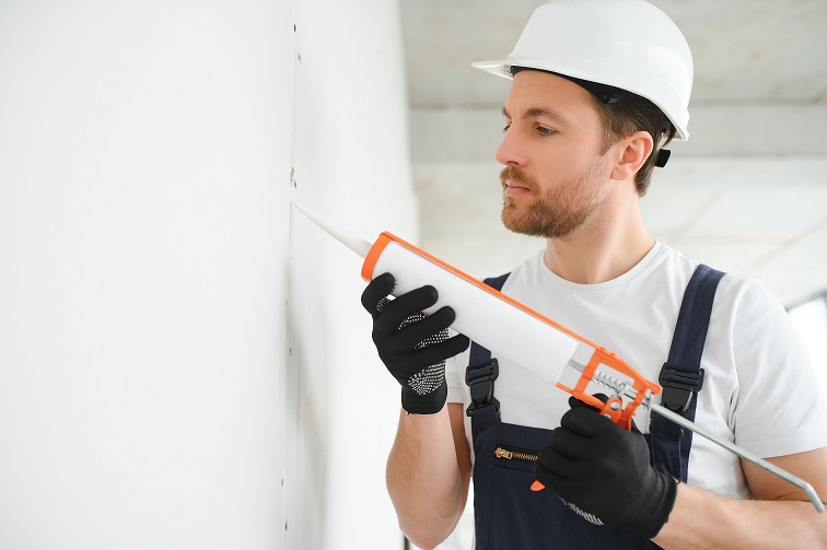 Professional Workman Applying Silicone Sealant With Caulking Gun on the Wall.